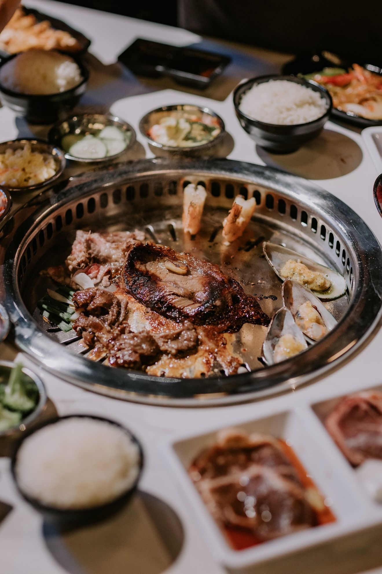 a plate of Korean BBQ food is sitting on a table next to bowls of food .