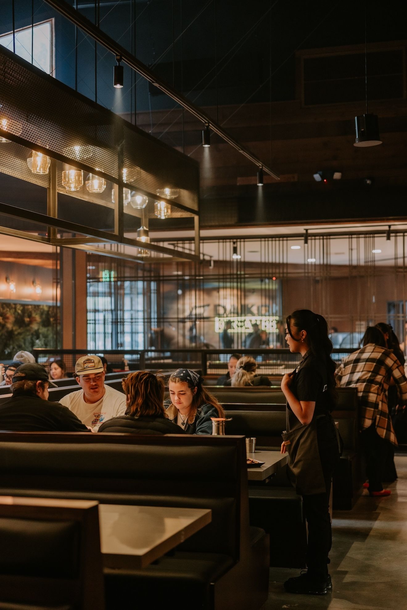 a group of people are sitting at tables in a restaurant .