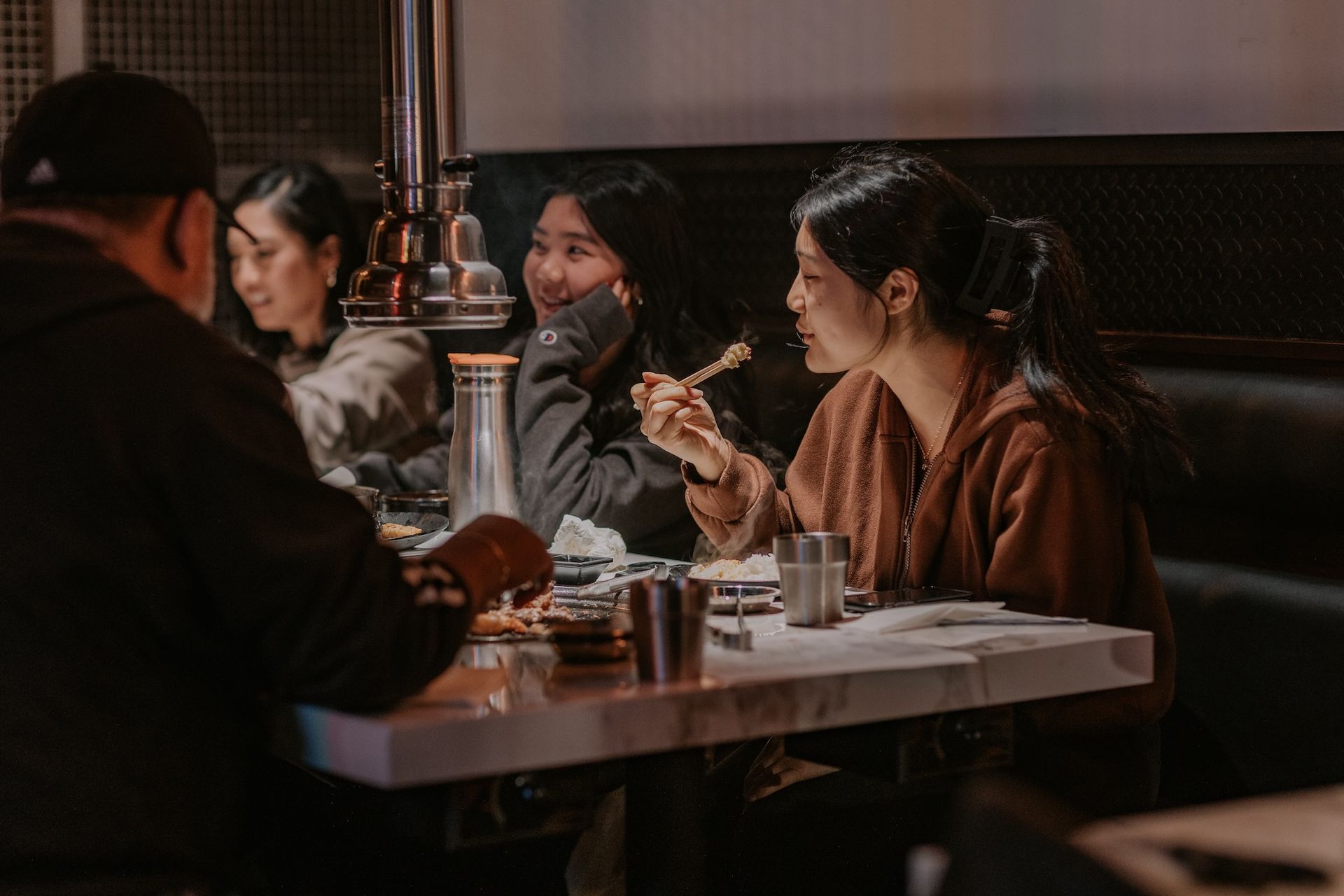 a group of people are sitting at a table in a restaurant eating food .