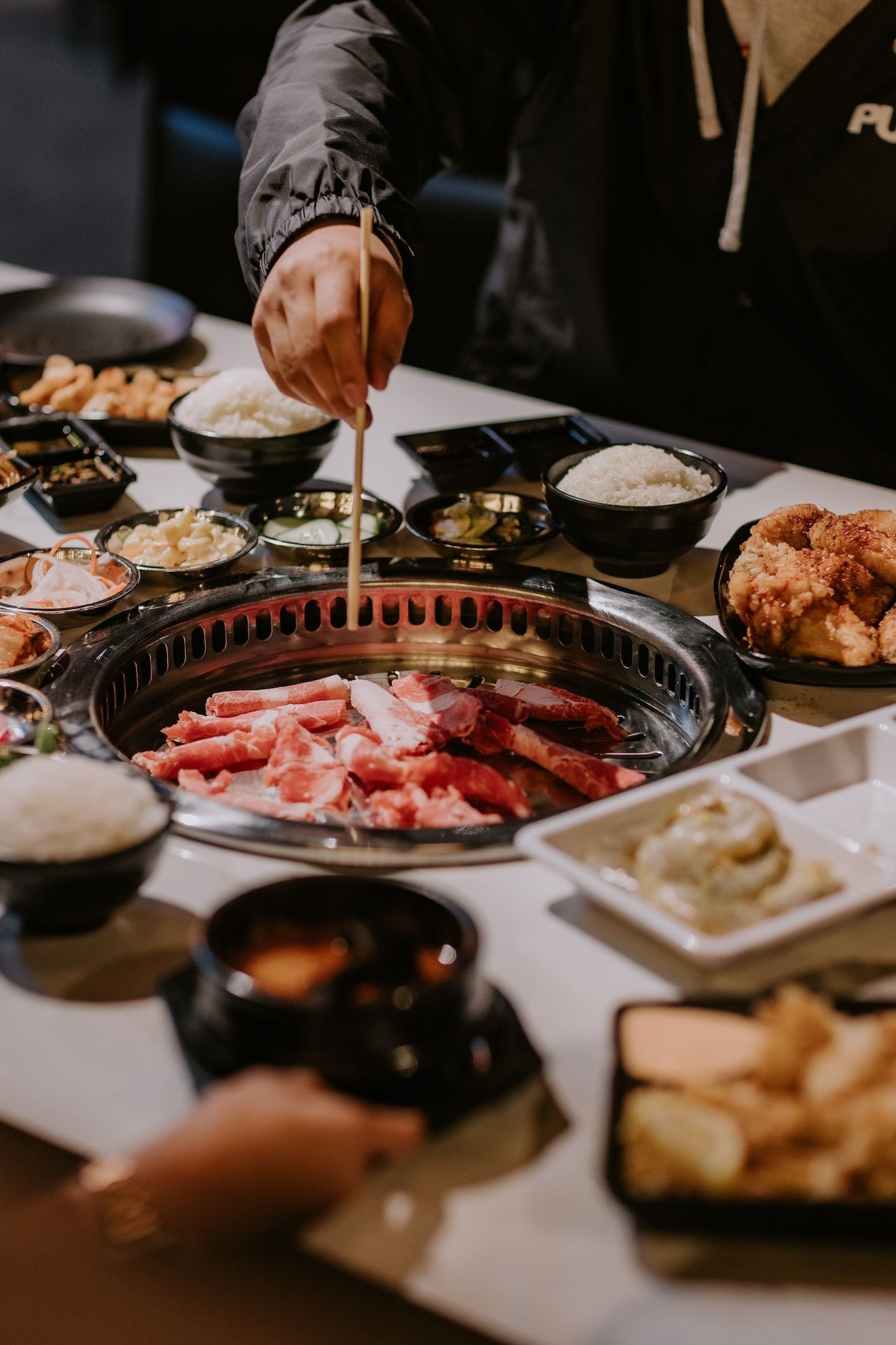 a person is eating Korean BBQ food with chopsticks at a table .