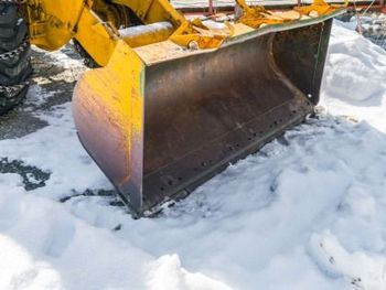 Yellow construction loader bucket resting in snow, close-up of the metal scoop.