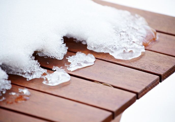 Snow melting on a wooden deck railing