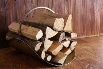 Basket of firewood logs on a wooden floor against a wood-paneled wall