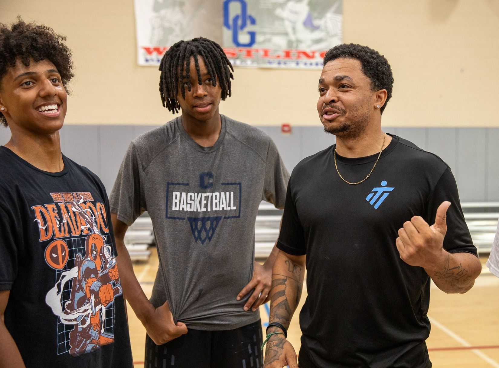 A man and two boys are standing next to each other on a basketball court.