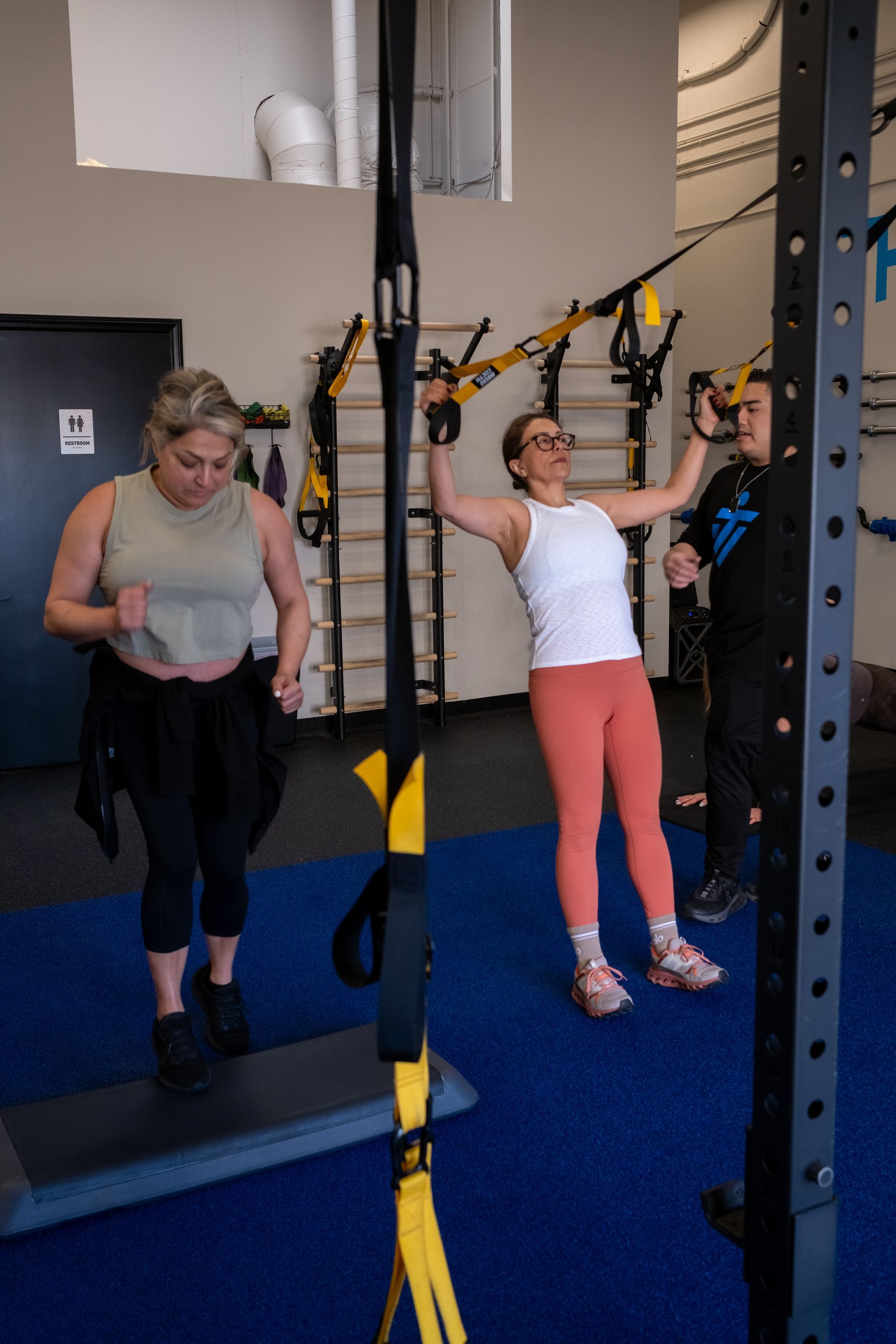 A group of women are doing trx exercises in a gym.