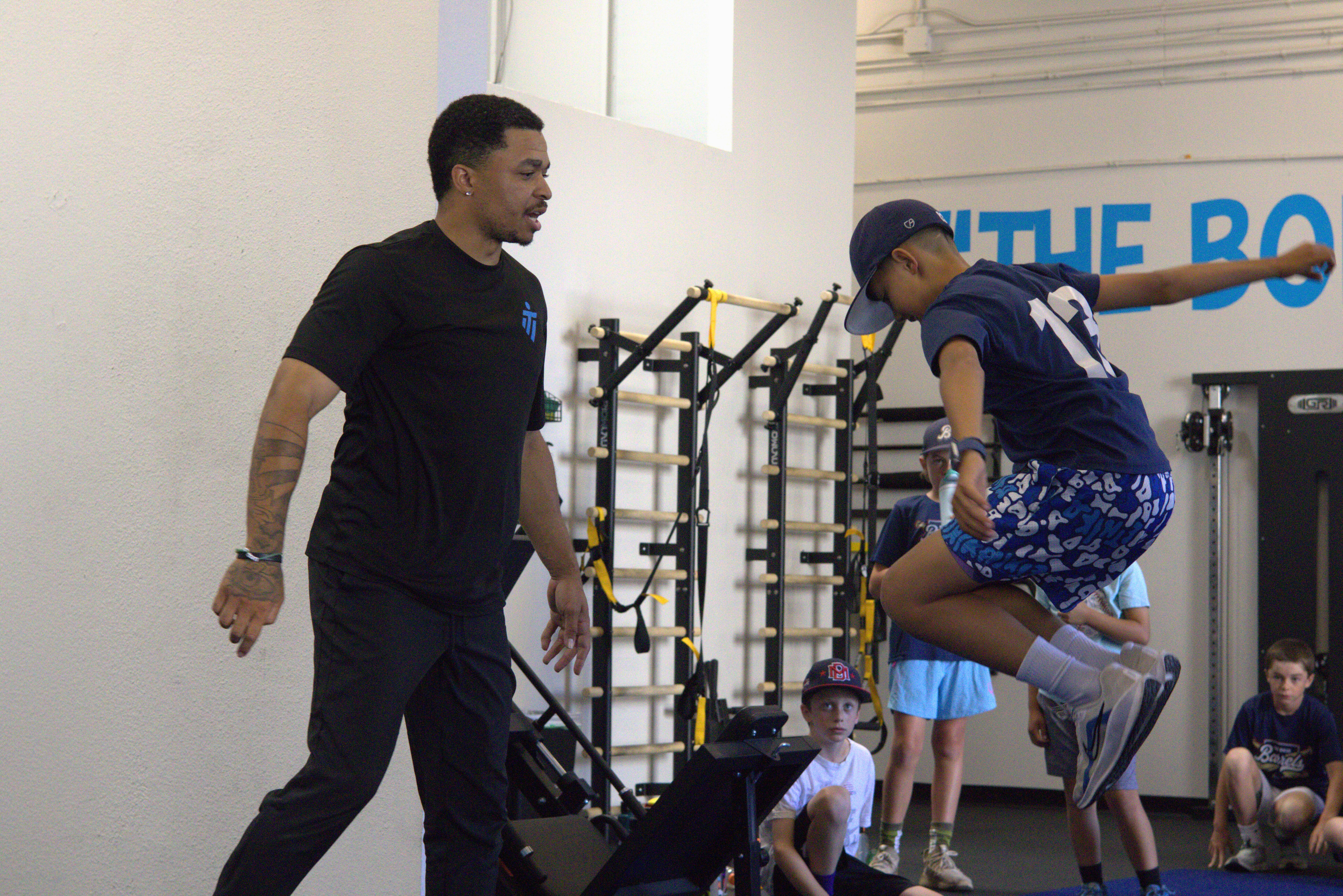 A man is helping a woman do exercises on a bench in a gym.
