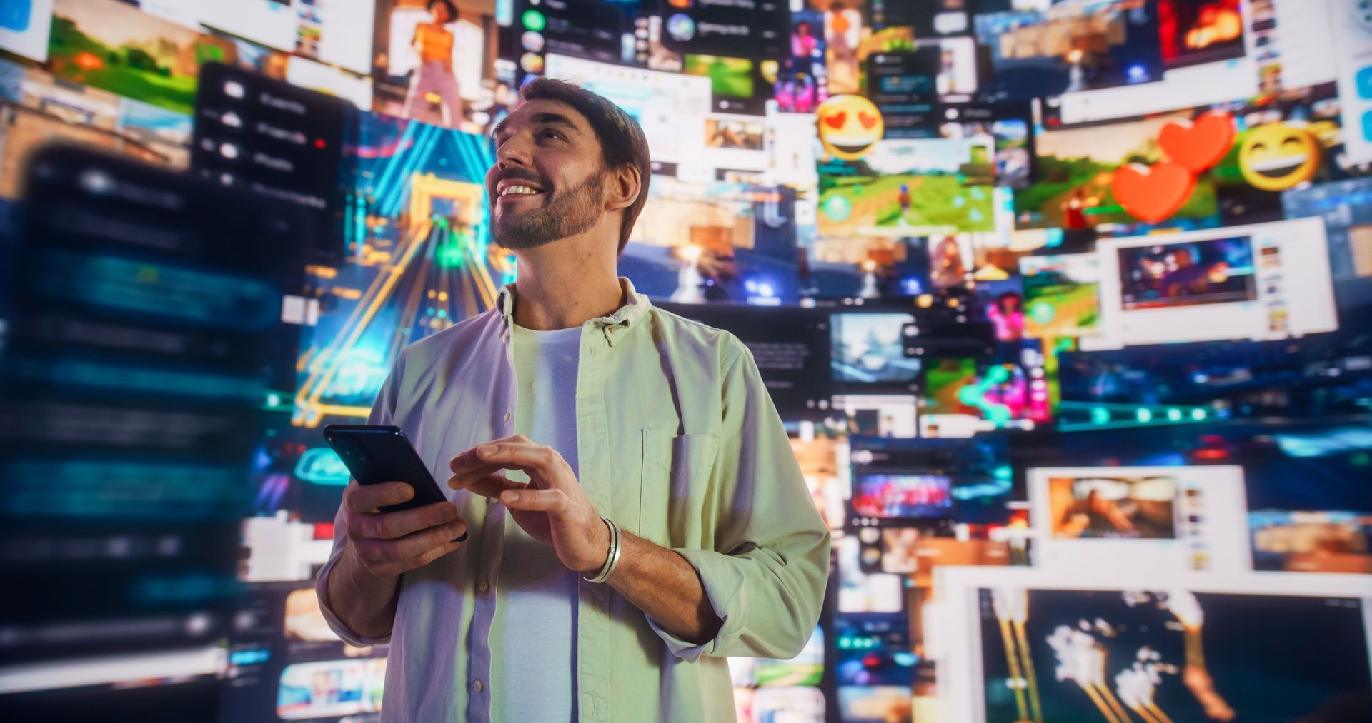 A man smiles while holding a smartphone against a background of glowing, tiled digital screens and social media icons.