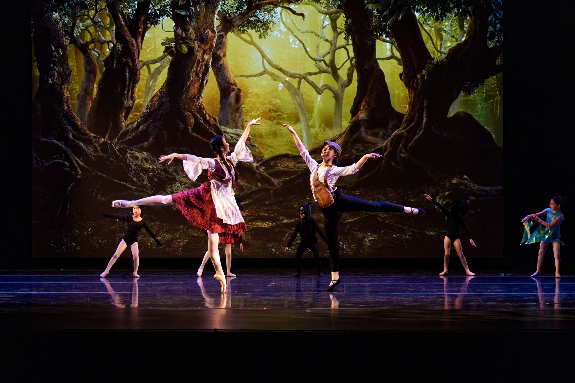 Ballet dancers on a stage with a painted forest backdrop, mid-leap in colorful costumes