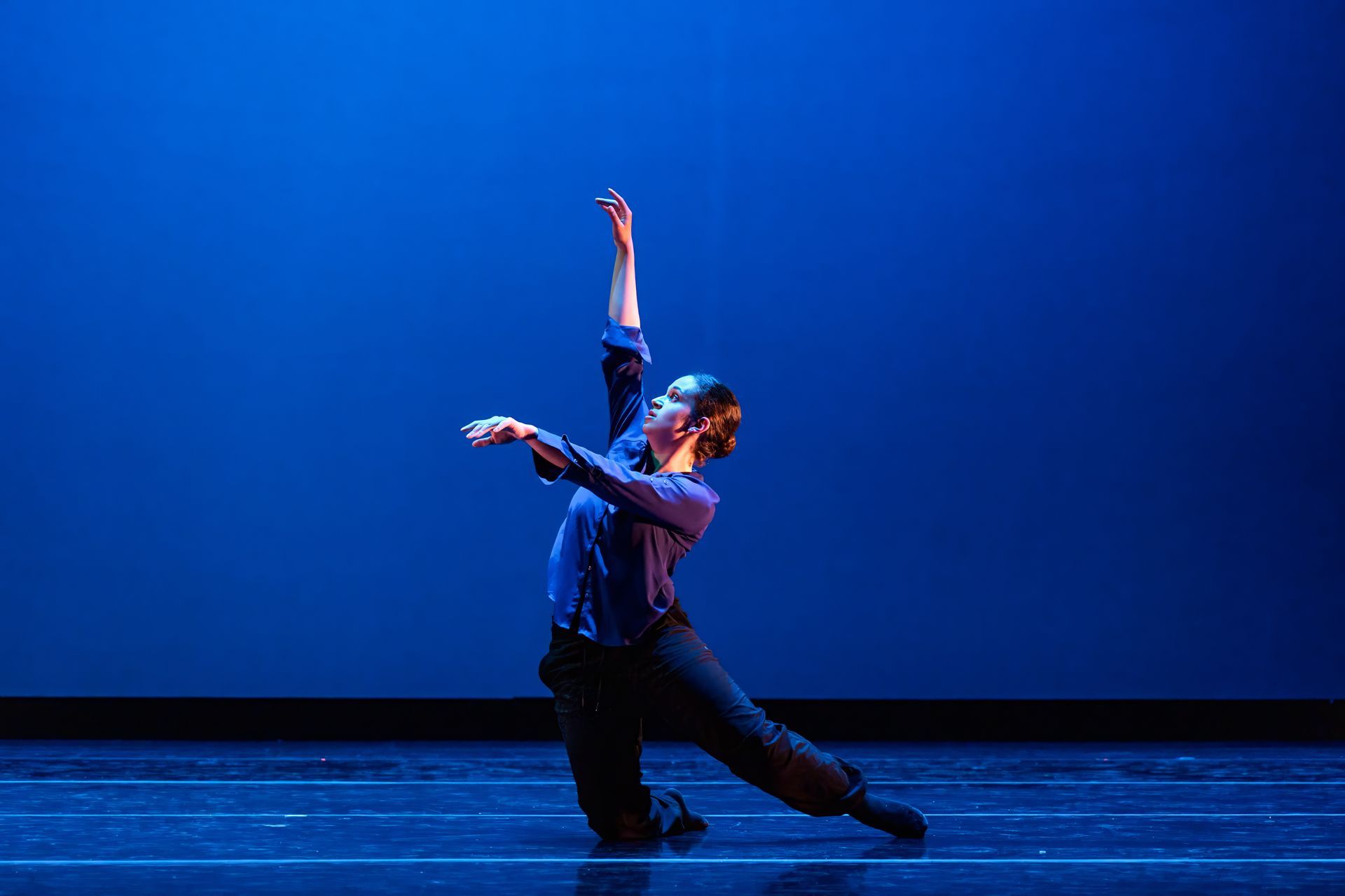 Dancer in blue lighting striking a dramatic pose on a stage