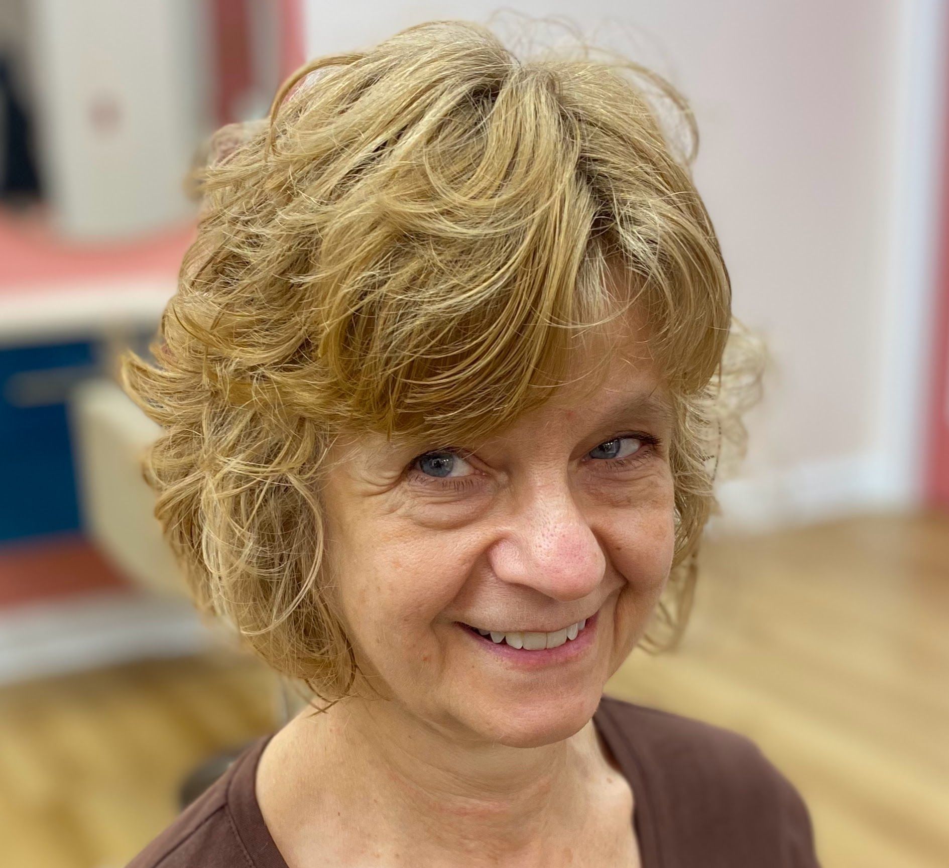 Smiling woman with short curly blonde hair in a bright indoor room