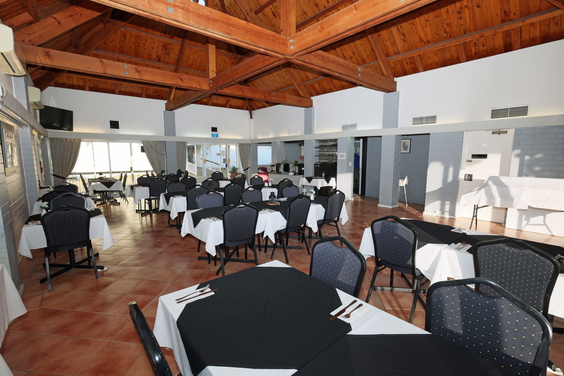 Banquet hall with round tables, white chair covers, and a wooden vaulted ceiling