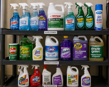 Three shelves of household cleaning products and spray bottles in a store aisle