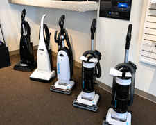 Row of upright vacuum cleaners on display in a store showroom