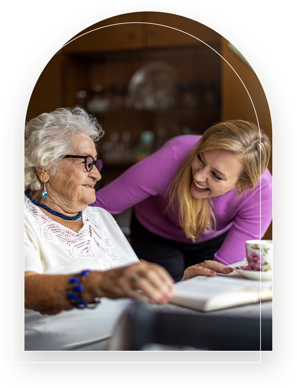 an elderly woman and younger woman smiling at each other
