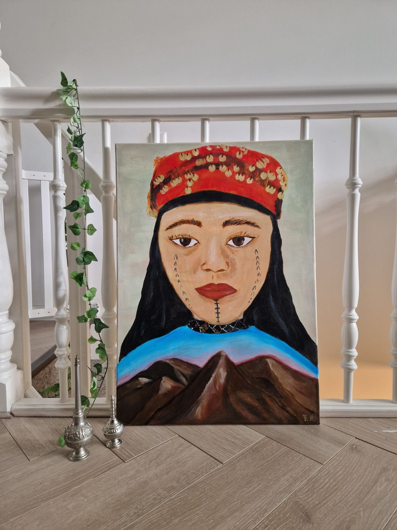 Schilderij Tashalhit van Fatiha Najid, acryl portret van Amazigh vrouw met bergen, ingelijst op blauwe achtergrond
