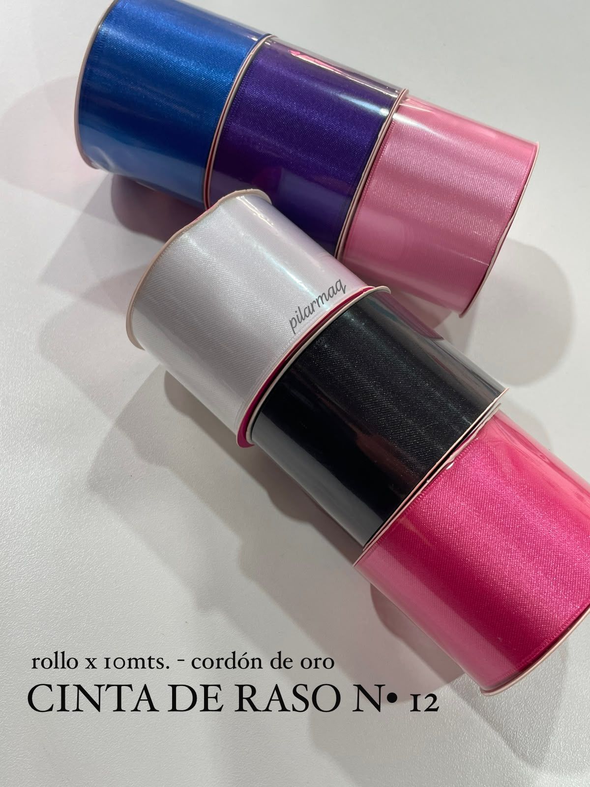 Bobinas de cinta de satén en azul, morado, rosa, blanco y negro sobre un fondo blanco.