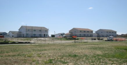 A row of houses are sitting on top of a lush green field.