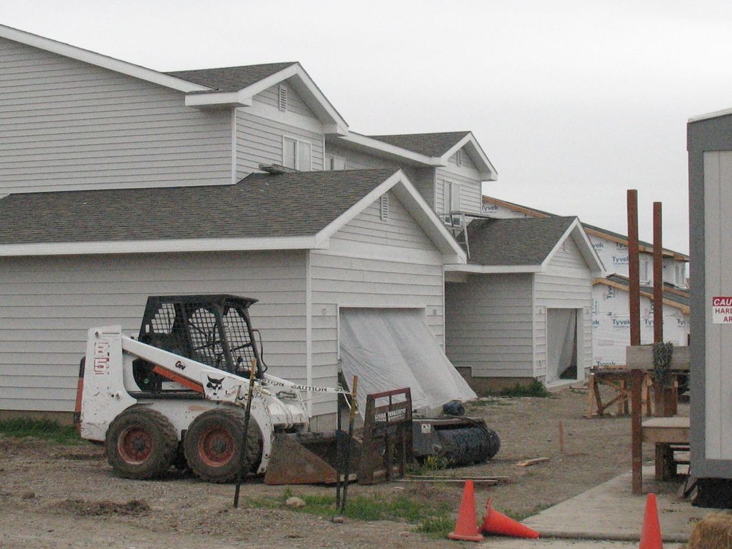 A bobcat is parked in front of a house under construction