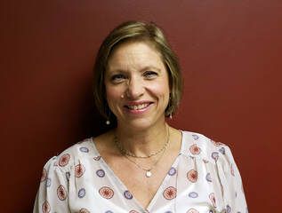 A woman is smiling for the camera in front of a red wall.