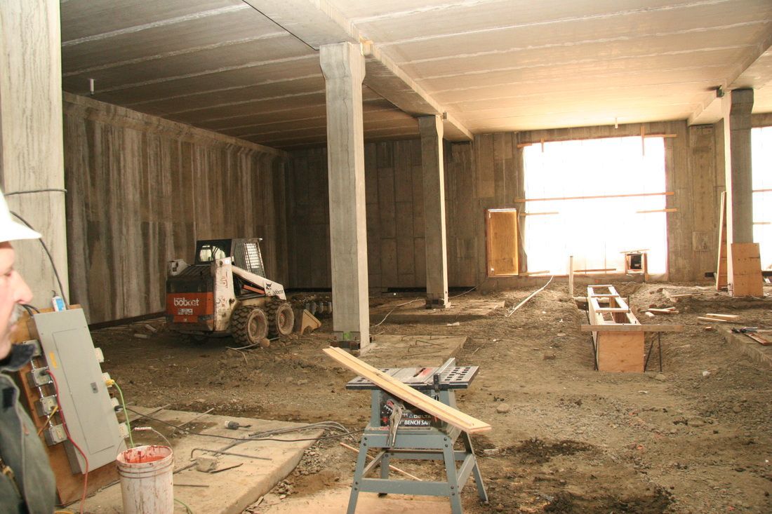 A man in a hard hat stands in a building under construction