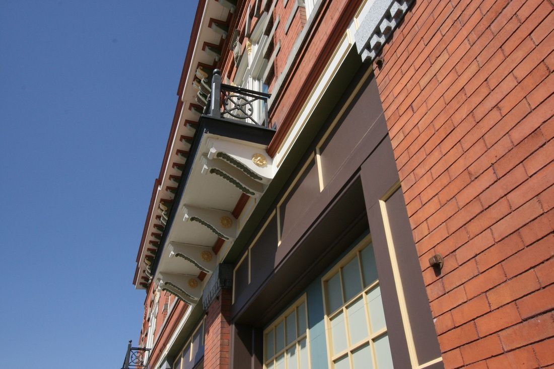 A brick building with a balcony and a blue sky in the background
