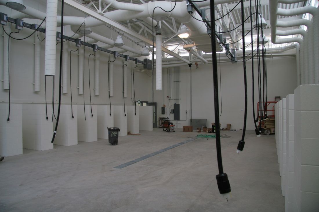 A large empty room with pipes hanging from the ceiling