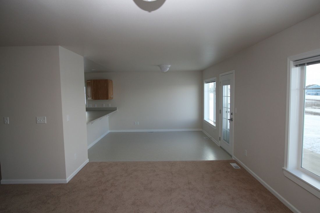 An empty living room with a carpeted floor and white walls