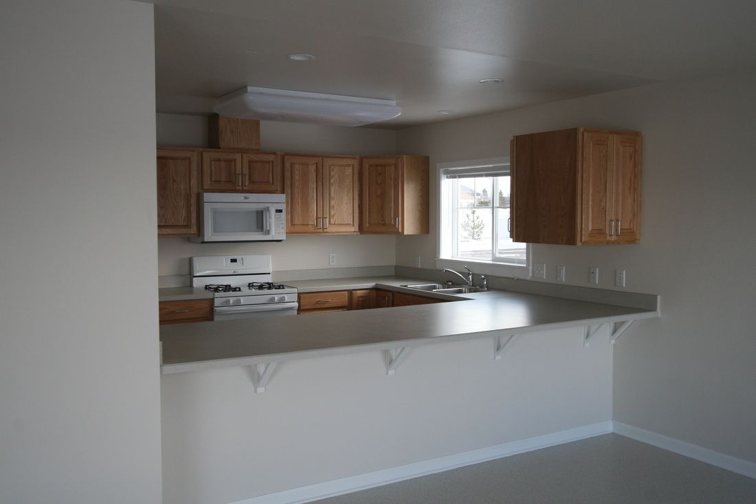 An empty kitchen with a stove and microwave