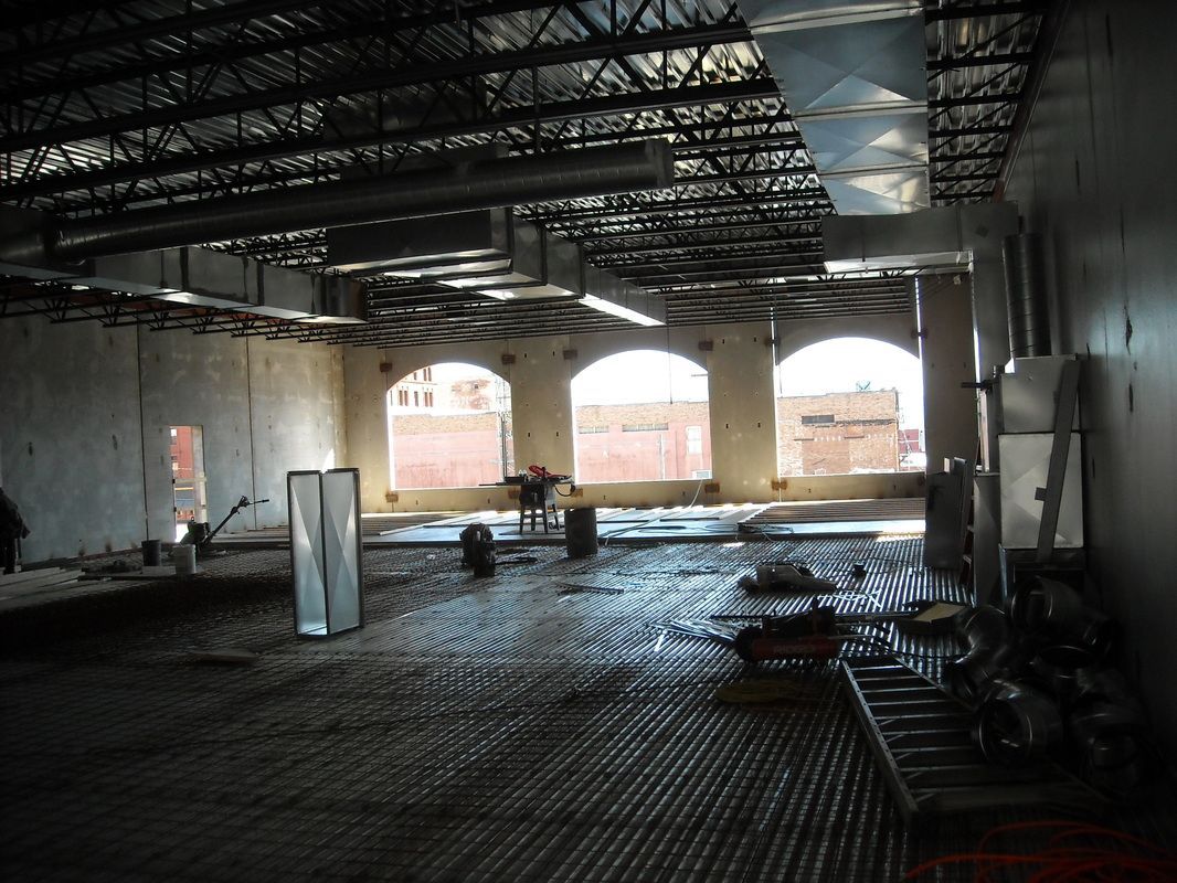 A large empty room with arched windows and a metal floor