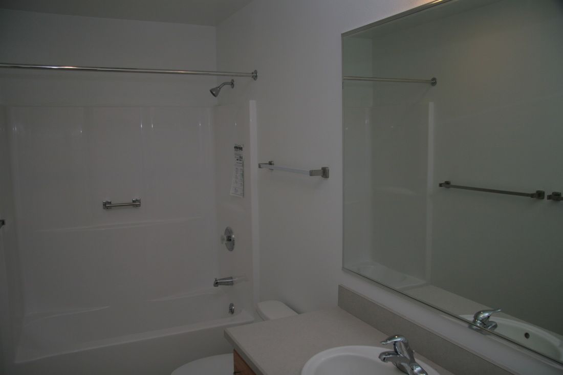A bathroom with a sink , toilet , shower and mirror.