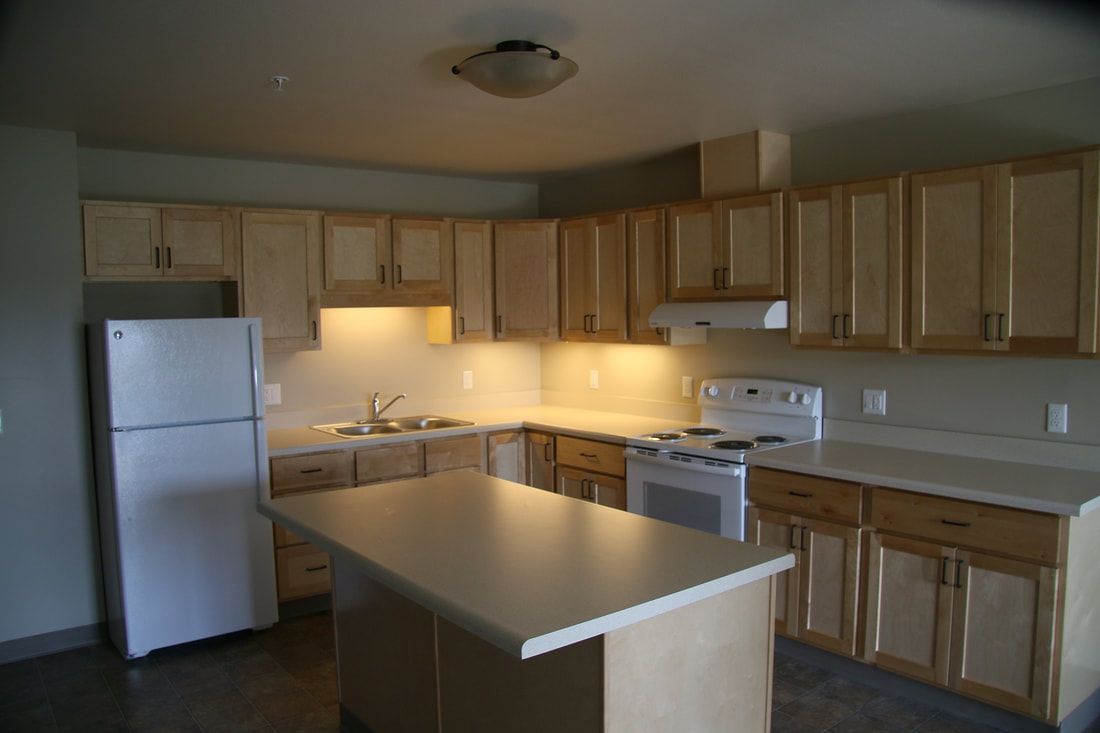 An empty kitchen with wooden cabinets and a white refrigerator