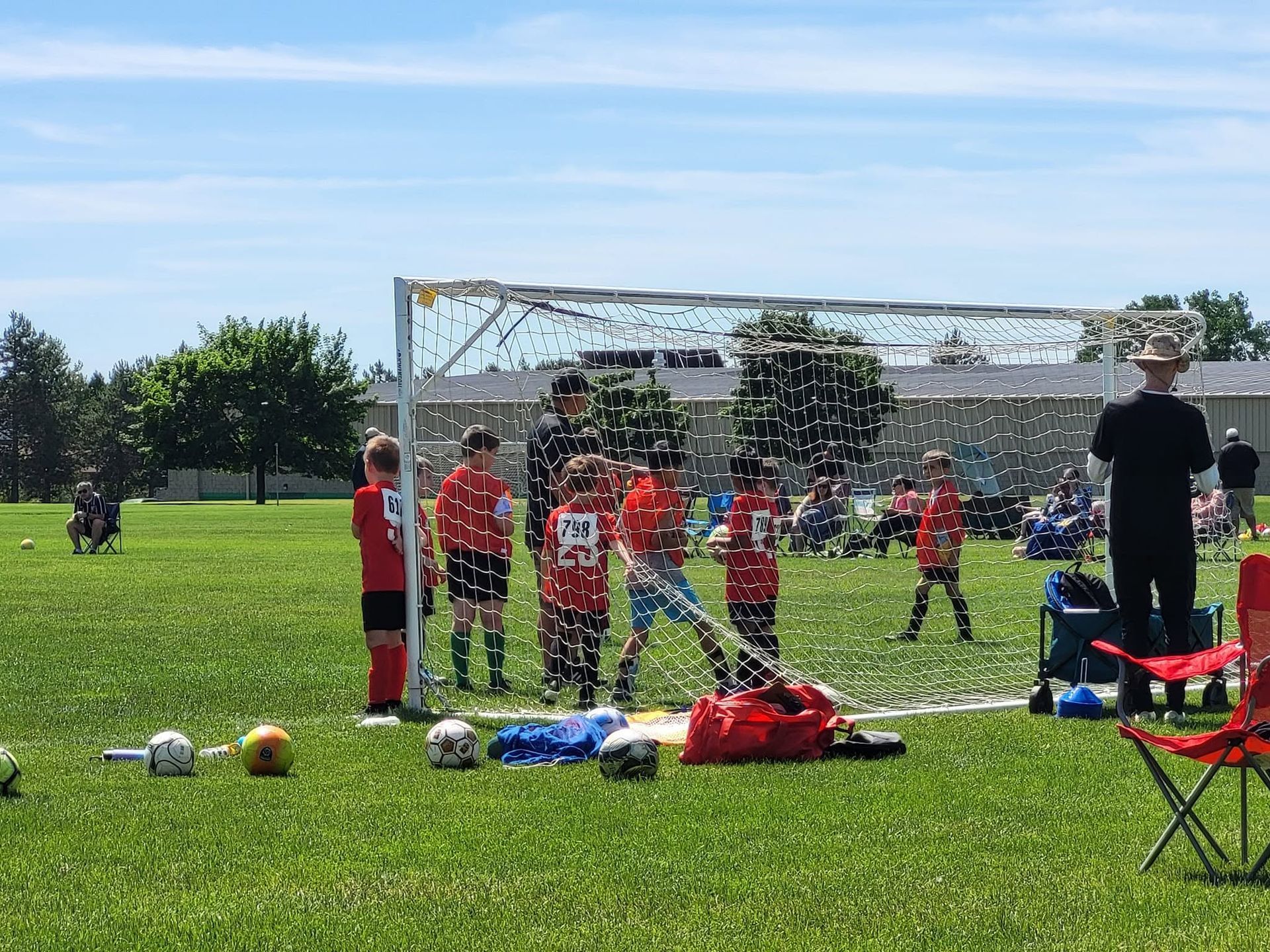 Youth soccer players in red uniforms near the goal on a sunny field