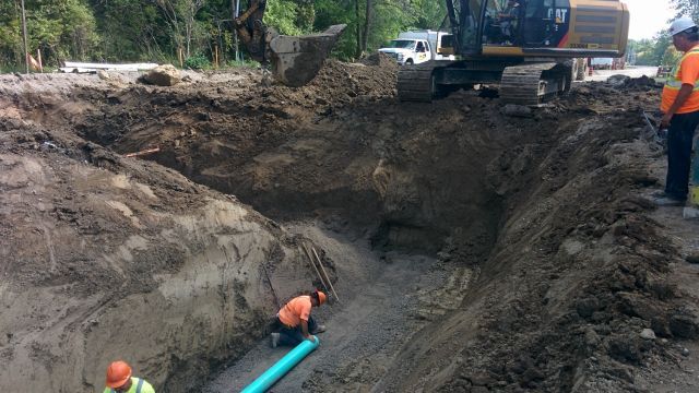 A group of construction workers are digging a hole in the dirt.