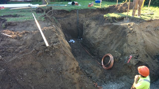 A man is standing in a large hole in the ground.