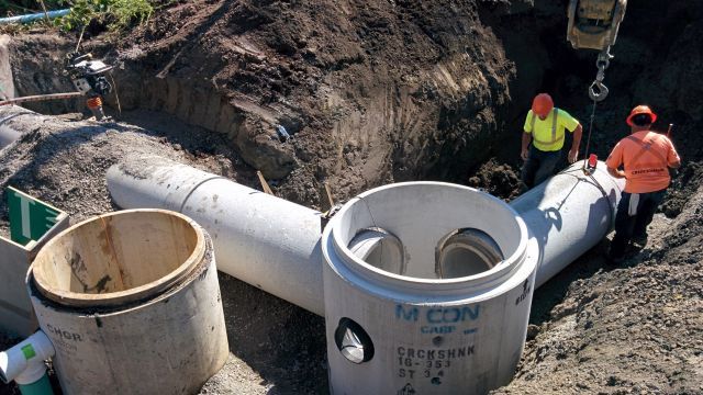 A group of construction workers are working on a drainage system