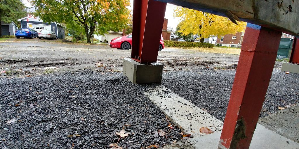 A red car is parked on the side of the road in a parking lot.