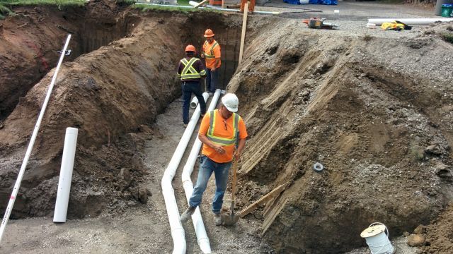A group of construction workers are working in a trench.