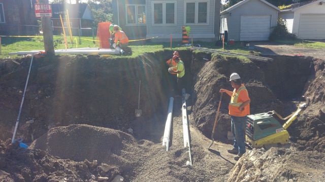 A group of construction workers are working on a hole in the ground.