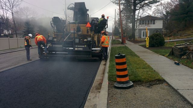A group of construction workers are working on a road.