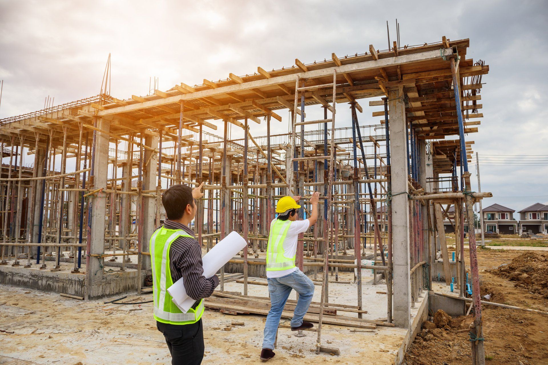 Two construction workers are standing in front of a building under construction.