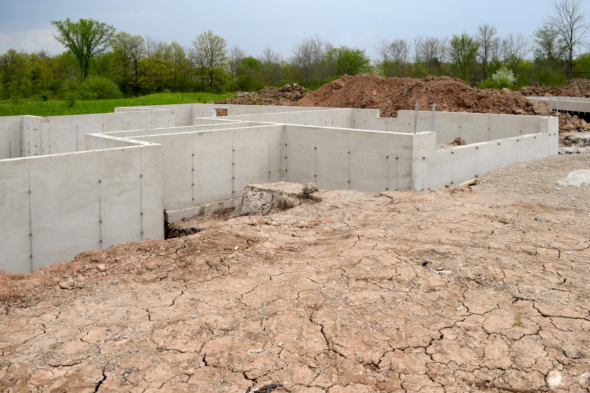A dry dirt field with a concrete foundation in the background