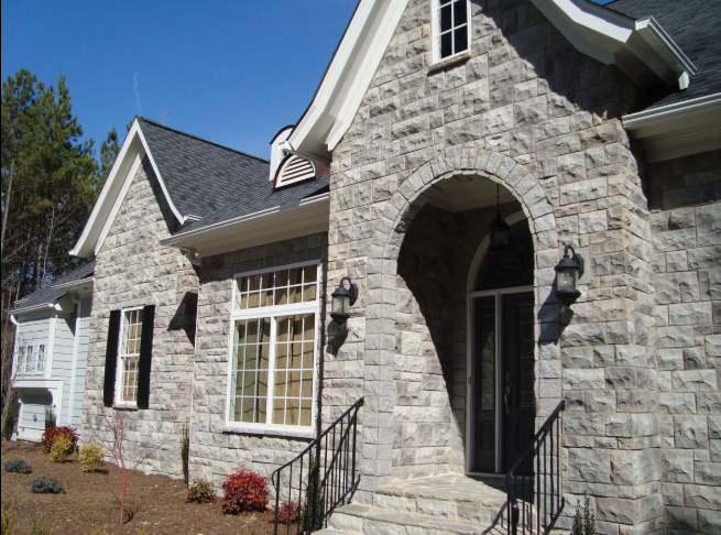 “Home exterior with a light stone masonry entryway, arched doorway, and clean finished walls from a masonry service in Pearland, TX”