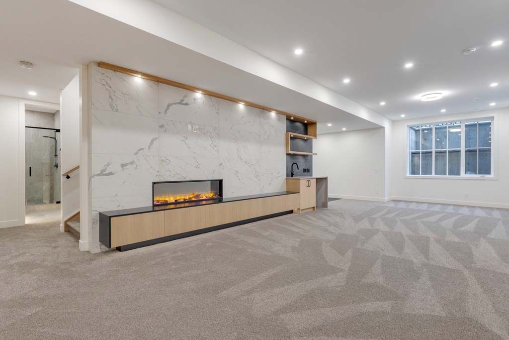 Modern basement with fireplace, wood accents, and light gray carpet. Includes built-in shelving and a window.