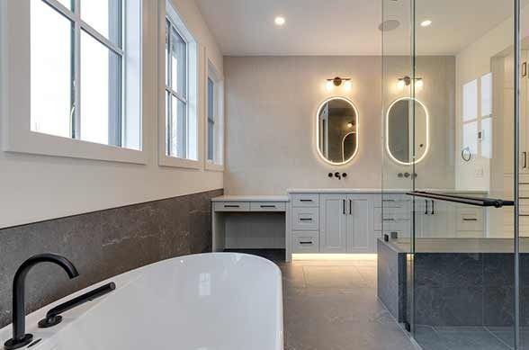 Modern kitchen with light wood floor, island with bar stools, brown cabinets, and overhead pendant lights.