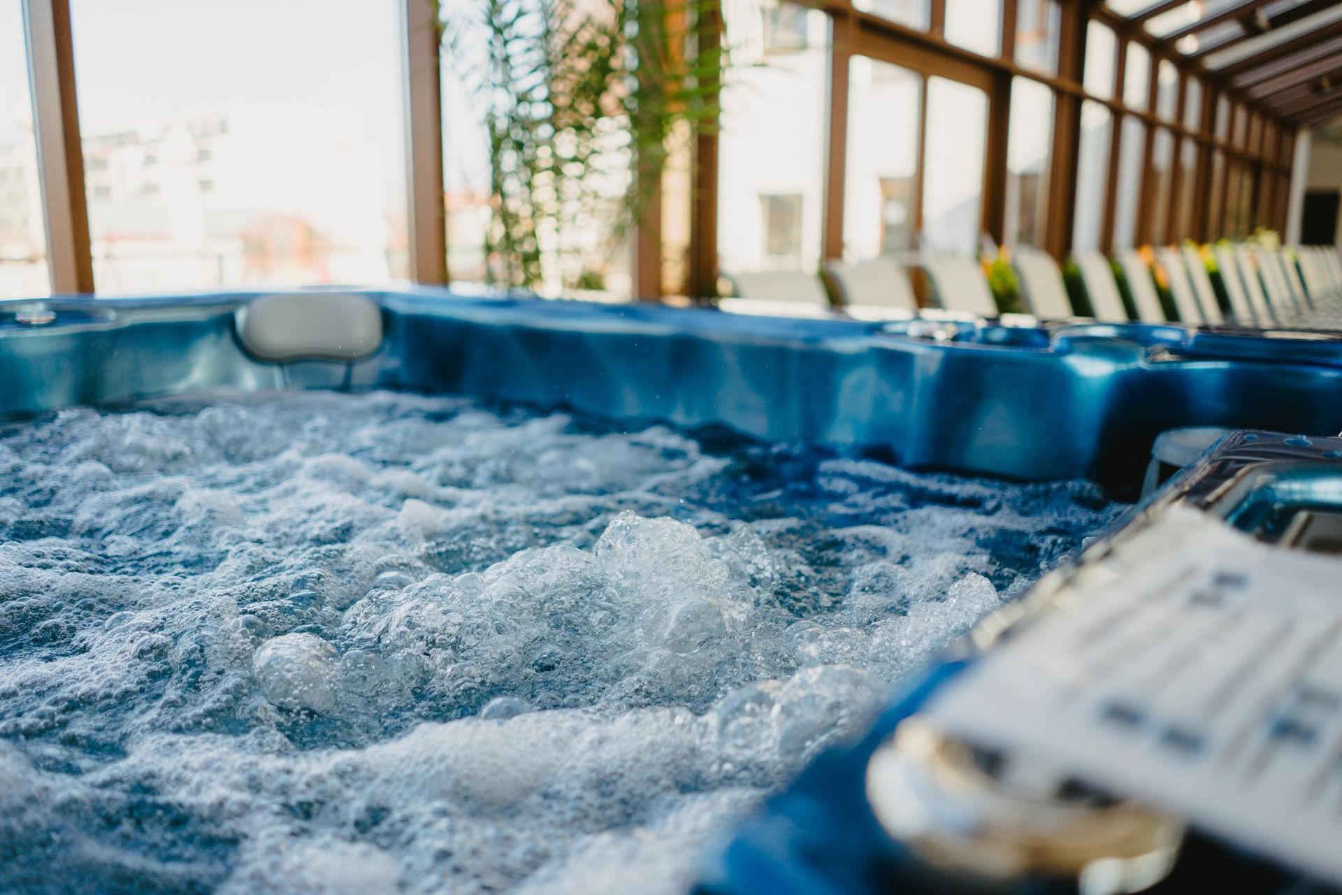 Bubbling blue jacuzzi with jets, indoors with natural light, potential for relaxation.
