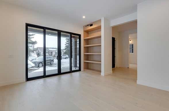 Modern kitchen with light wood floor, island with bar stools, brown cabinets, and overhead pendant lights.