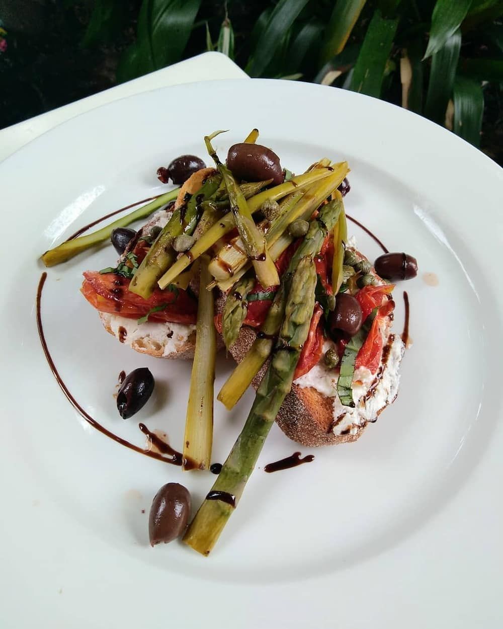 A White Plate Topped With Asparagus Olives And Tomatoes — Vines at 139 in Grafton, NSW