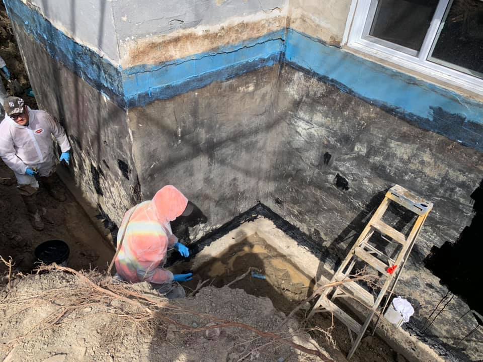 Deux ouvriers creusent et préparent une tranchée pour l'installation d'un système de drainage.