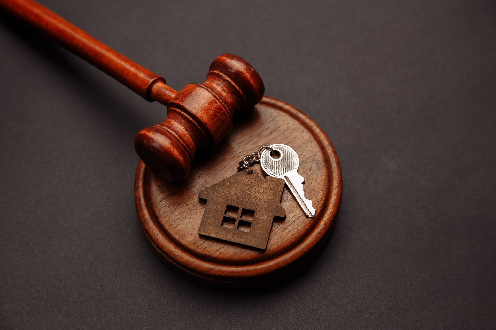 Wooden gavel on a sound block with house key, suggesting real estate auction.