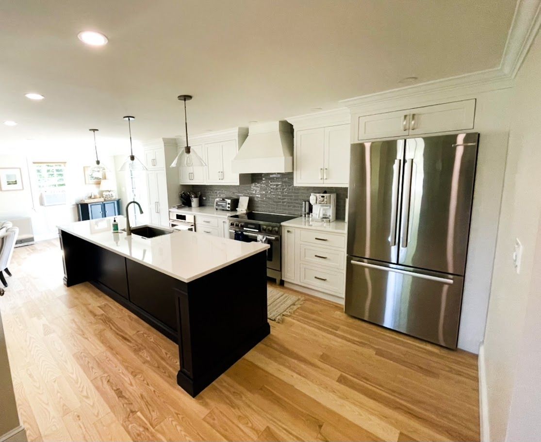 Bright modern kitchen with white cabinets, black island, stainless steel appliances, and hardwood floors